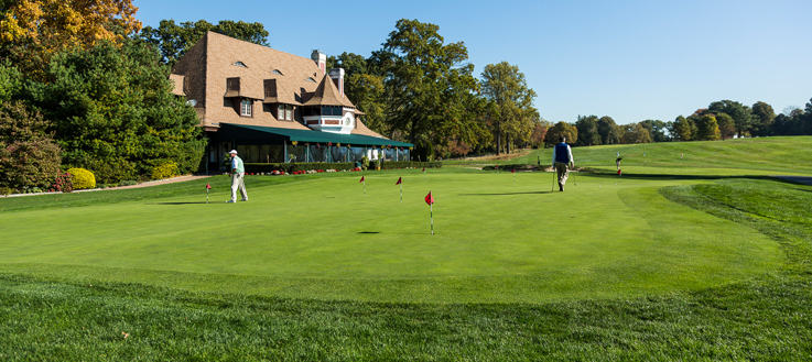 players on a golf course with the clubhouse in the background