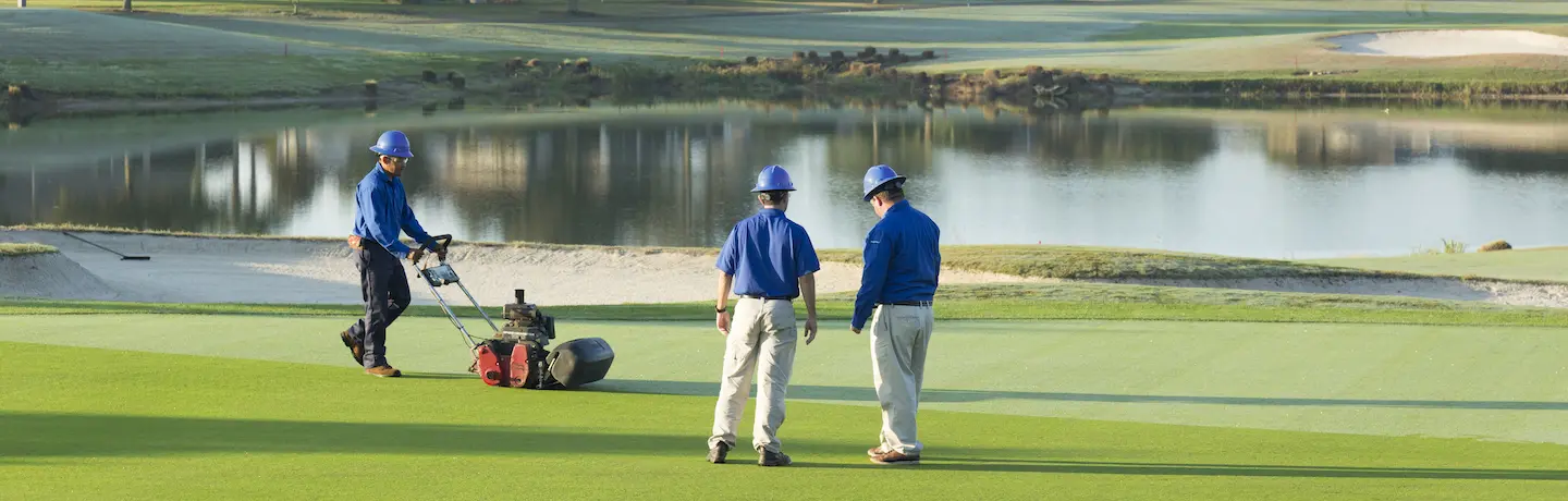crew members mowing and inspecting golf course