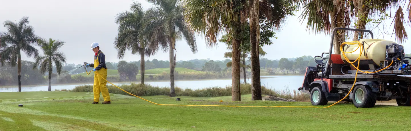 golf course maintenance crew member spraying control products
