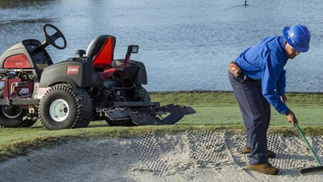 golf course maintenance crew raking bunker