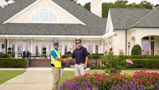 landscaper and property manager shaking hands on lawn