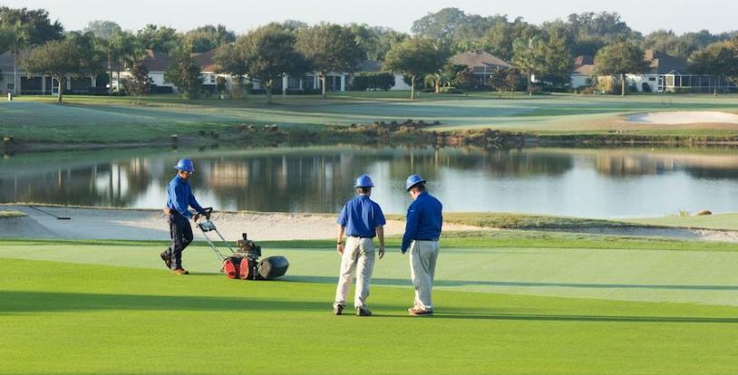 crew members mowing and inspecting golf course