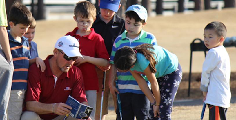 golf instructor talking to young golf students