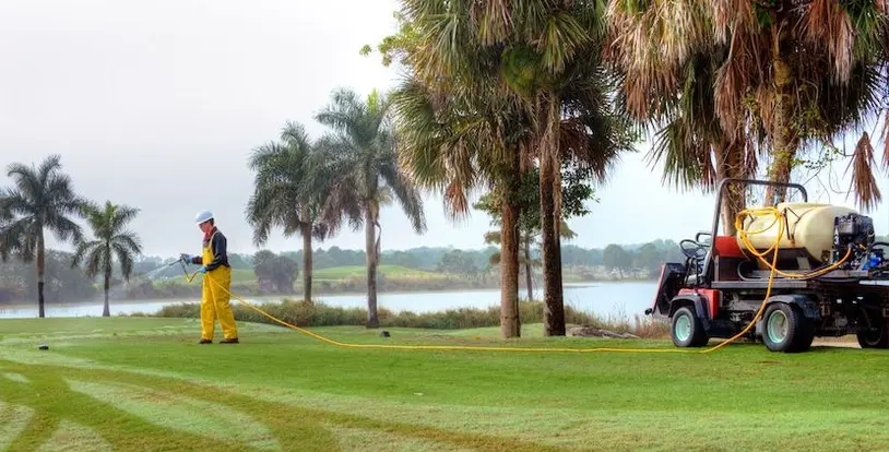golf course maintenance crew member applying a turf application