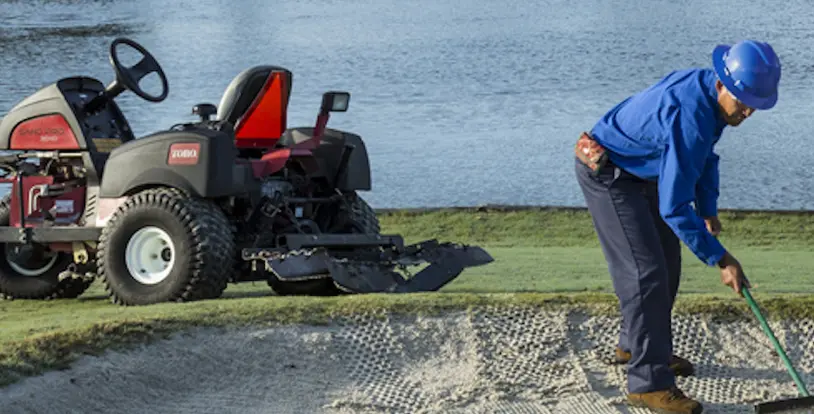 golf course maintenance crew raking bunker